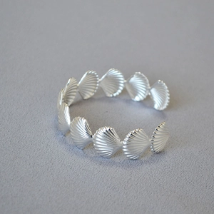 Detailed close-up of silver-tone seashell motif open bangle featuring textured scallops