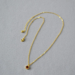 Close-up of golden O-chain necklace with square orange zircon pendant and lobster clasp