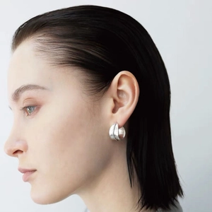 Boucles d'oreilles créoles irrégulières en C argentées au fini mat portées par un mannequin