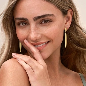 Elegant gold drop earrings with a minimalist spindle design on a model's ear