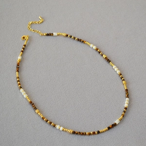 Dettaglio della collana di perline con pietre occhio di tigre e perle dorate e chiusura