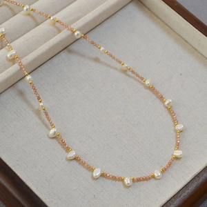 Detail view of handmade necklace with orange beads and natural freshwater pearls