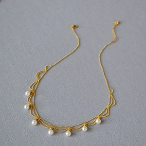 Détail de collier perles vintage doré avec franges ondulées et fermoir mousqueton chic