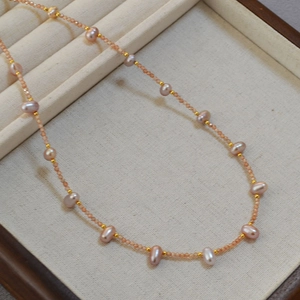 Detail of pink freshwater pearl necklace with sunstone beads and gold spacers in a jewelry box