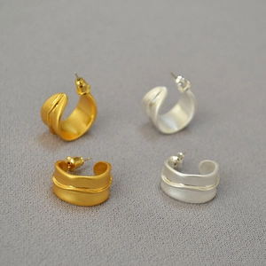 Vue détaillée de boucles d'oreilles irrégulières en C, finitions mate or et argent