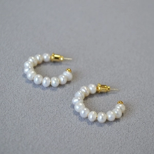 Détail de boucles d'oreilles élégantes en perles d'eau douce en forme de C doré chic