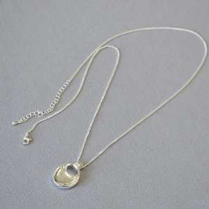 Macro detail of silver saddle pendant showing high-polish mirror finish and O-chain