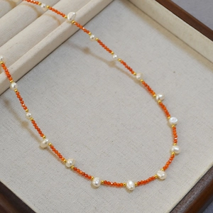 Macro view of freshwater pearl and orange carnelian beaded necklace in a jewelry tray