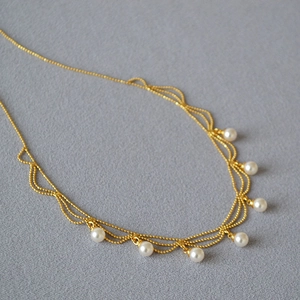 Collier vintage français doré avec 7 perles blanches élégantes sur tissu texturé