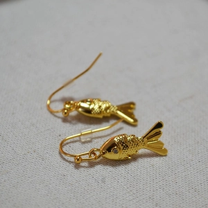 Detailed view of gold fish earrings showing fine scale texture and micro zircon eyes