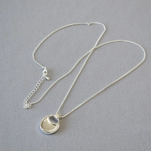 Detailed close-up of a silver saddle bag pendant necklace with high-polished mirror finish
