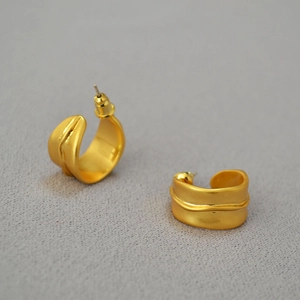 Vue détaillée des boucles d'oreilles C dorées mates aux bords ondulés irréguliers
