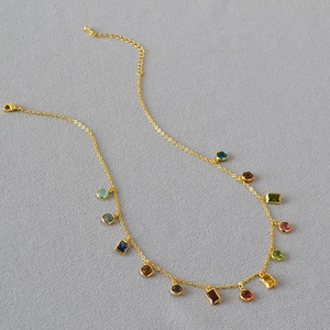 Detail of gold chain necklace with colorful zircon gemstones and lobster clasp closure