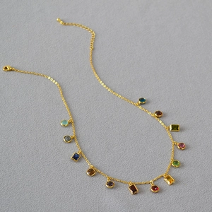 Detail of gold plated necklace featuring multi-colored zircon stones on a fine chain