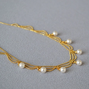 Détail macro du collier français vintage à trois rangs dorés avec pendentifs perles
