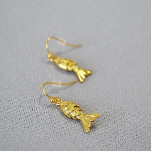 Close-up of gold fish earrings showing detailed scale textures and sparkling crystal eyes