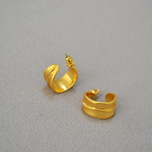 Vue détaillée des boucles d'oreilles irrégulières en C plaqué or avec texture mate ondulée
