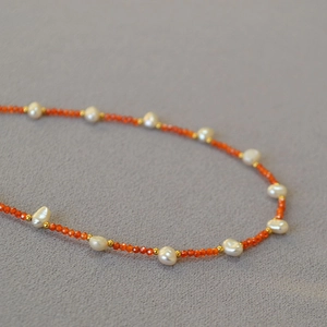 Macro detail of orange beaded necklace with baroque freshwater pearls and gold spacers