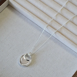 Macro shot of silver saddle pendant necklace on beige fabric jewelry display box