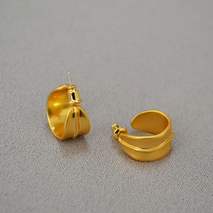 Détail de boucles d'oreilles dorées en forme de C avec design strié et fini mat