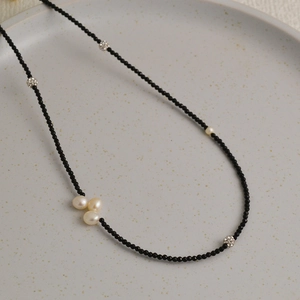Détails d'un collier artisanal en perles de spinelle noire sur un plateau en céramique