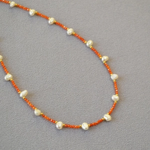 Detail of freshwater pearl necklace with orange agate beads and gold metal spacers