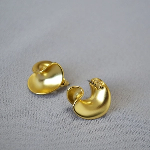 Close-up of matte gold vintage twisted C-shape earrings with a textured petal design