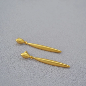 Detailed macro view of gold-plated matte brass earrings with elegant long linear drops