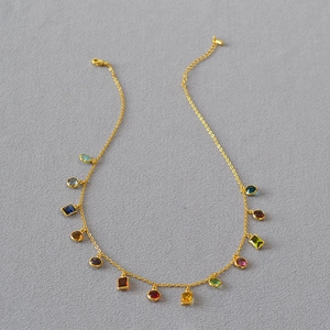 French vintage gold-plated necklace with colorful zircon pendants on gray fabric