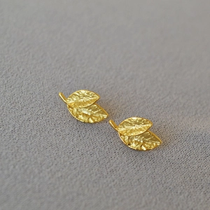 Detailed macro view of gold-plated leaf stud earrings with realistic vein texture