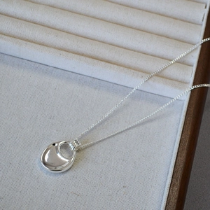Macro shot of silver organic saddle-shaped pendant with mirror polished surface