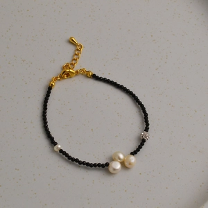 Détail d'un bracelet de perles noires facettées et perles blanches sur un plateau