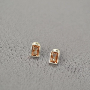Macro shot of rectangular champagne zirconia earrings with silver-toned metal settings