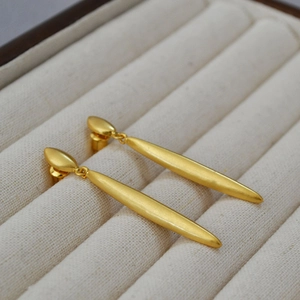 Detail of elegant gold-plated drop earrings featuring a matte finish and minimalist long design