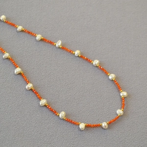Detail of freshwater pearl necklace with orange faceted beads and golden accents