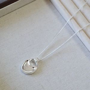 Detail view of a silver saddle bag pendant necklace on a textured jewelry tray