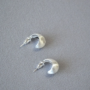 Detailed close-up of matte silver teardrop earrings with brushed metallic texture