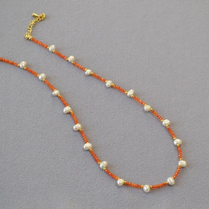 Detail of freshwater pearl and orange bead necklace with gold metallic spacer beads