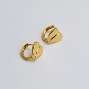 Detailed view of gold plated huggie hoop earrings with faceted 3D heart charms