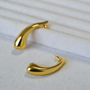 Exaggerated golden brass teardrop earrings with a polished mirror finish on white display
