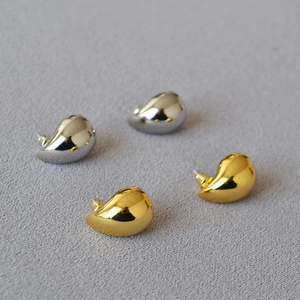 Detail of high-polish hollow teardrop stud earrings in gold and silver finishes