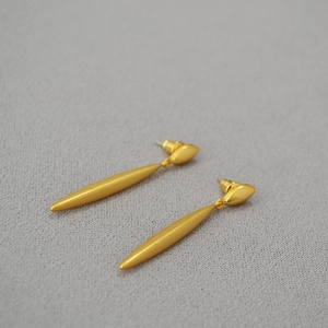 Macro detail of matte gold long drop earrings featuring a sleek marquise stud and tapered bar