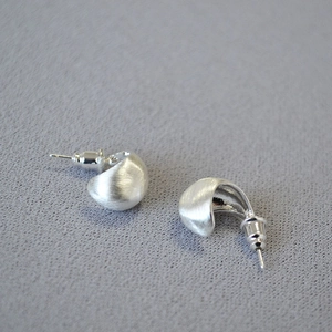 Macro shot of brushed silver-plated brass earrings with a minimalist teardrop shape