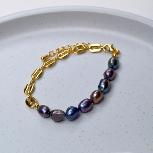 Détail du bracelet chaîne en or avec des perles baroques aux reflets irisés