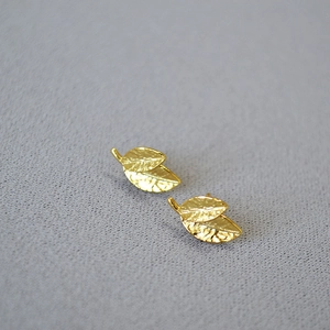 Detail showing the intricate leaf vein texture and golden plating on these stud earrings