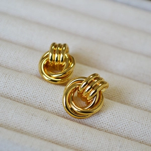 Close-up of gold-plated knotted earrings with a polished multi-ring twisted design