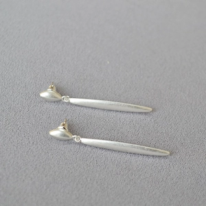 Close-up of minimalist matte silver long bar earrings with elegant oval stud design