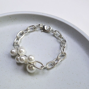 Détail d'un bracelet à gros maillons argentés avec perles élégantes et fermoir homard