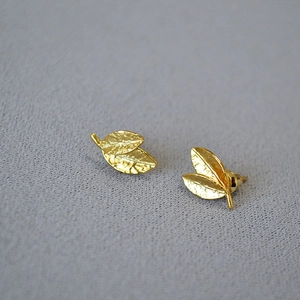 Detailed view of leaf-shaped gold earrings with hammered texture and intricate vein patterns