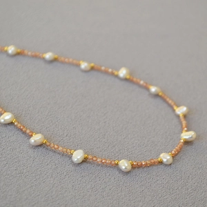 Macro shot of freshwater pearls and orange beads on a handmade beaded necklace